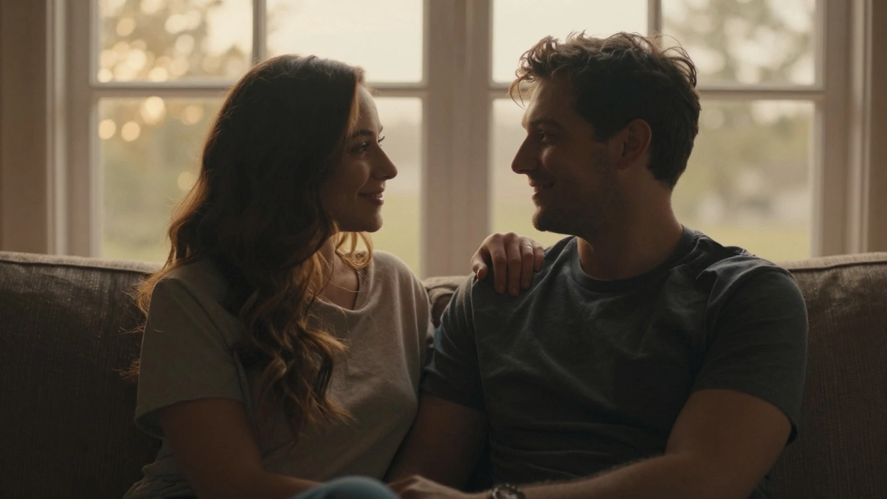 Een man en vrouw zitten dicht bij elkaar op de bank, een zachte aanraking, hun gezichten lichtend in het avondlicht.