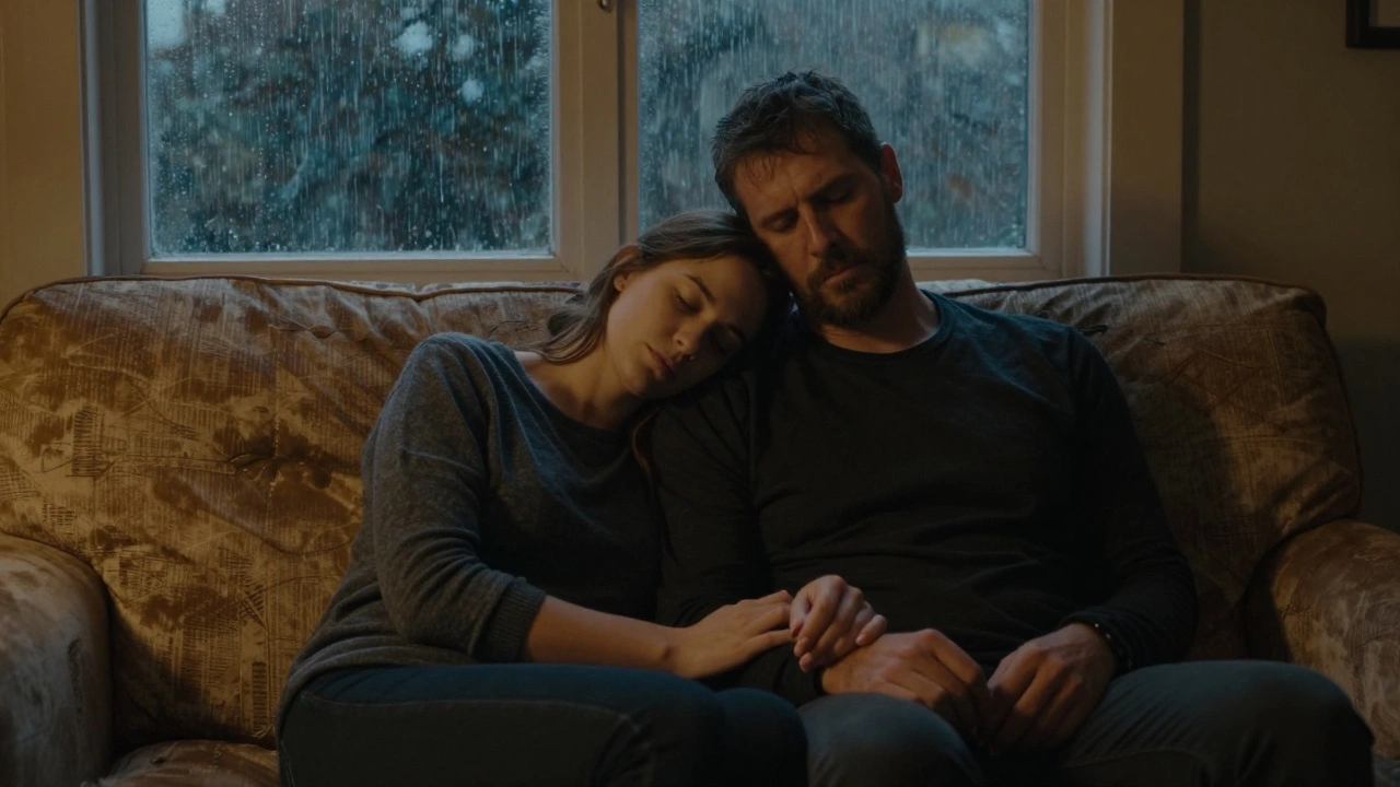 Een man en vrouw zitten stilletjes naast elkaar op de bank, hun handen samengevouwen in stilte.