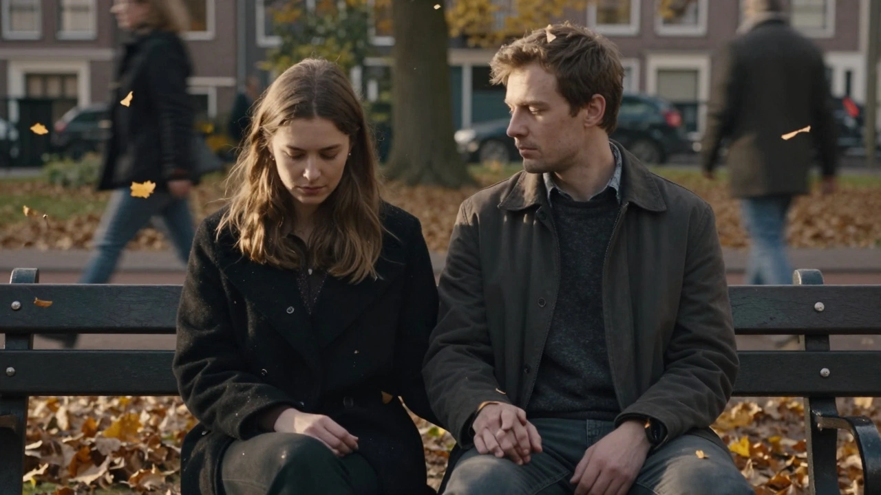 Een man houdt de hand van een vrouw op een bank, herfstbladeren zweven rond, stilte en verbinding.